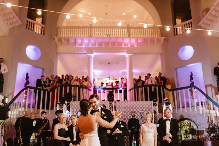 bride and groom enjoying their first dance while their guests watch from the stairs at the Lightner Museum