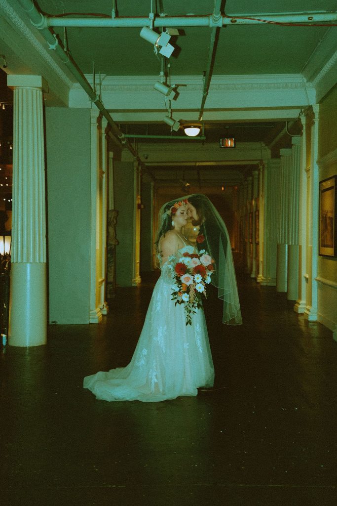 bride and groom under veil in hallway with vintage filter
