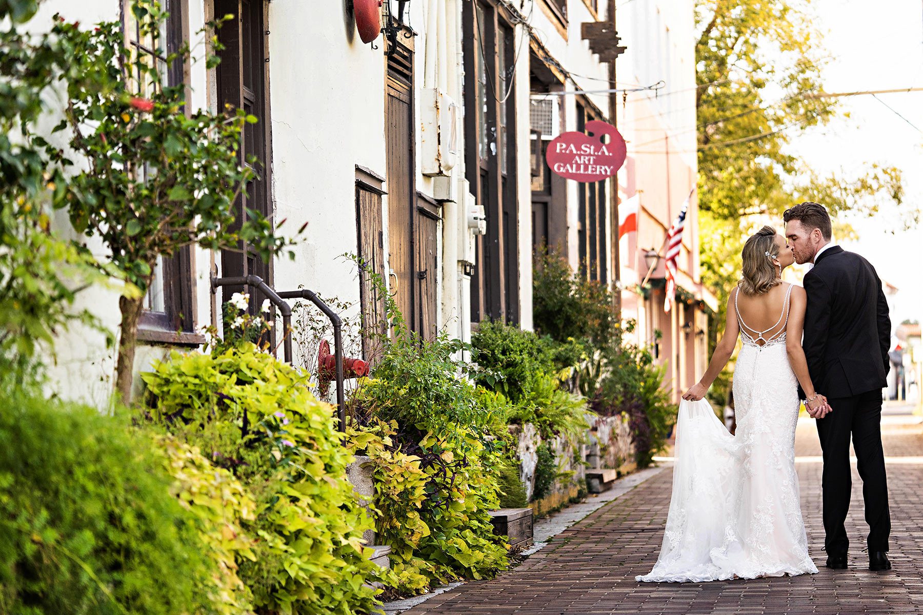 bride and groom kissing and holding hands while walking down streets of St. Augustine