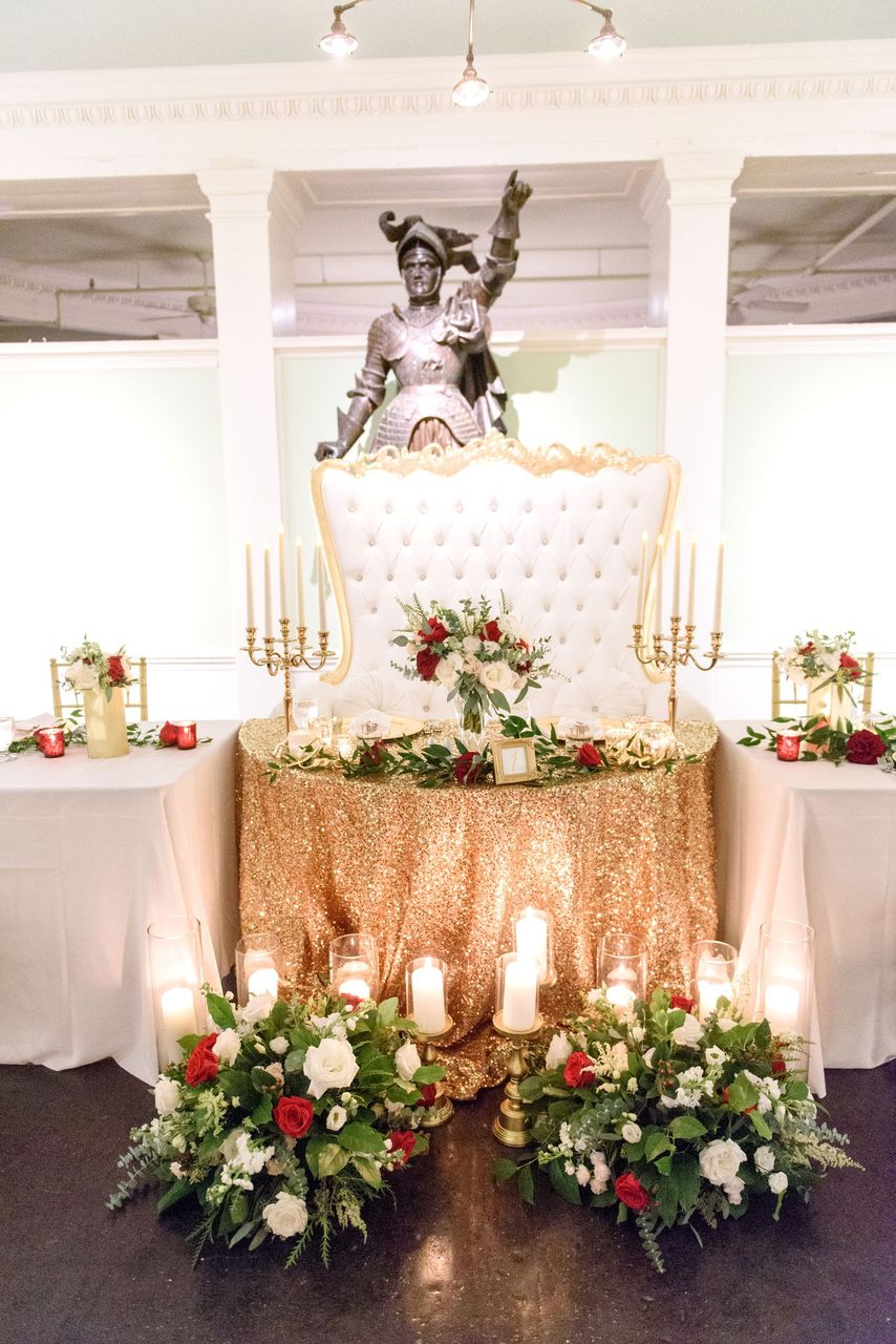 wedding sweetheart table with red and green florals and gold glitter tablecloth