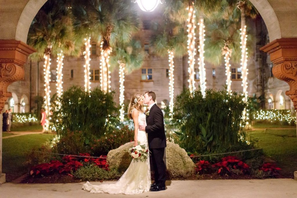 bride and groom kissing outside of the Lightner Museum with trees lit up
