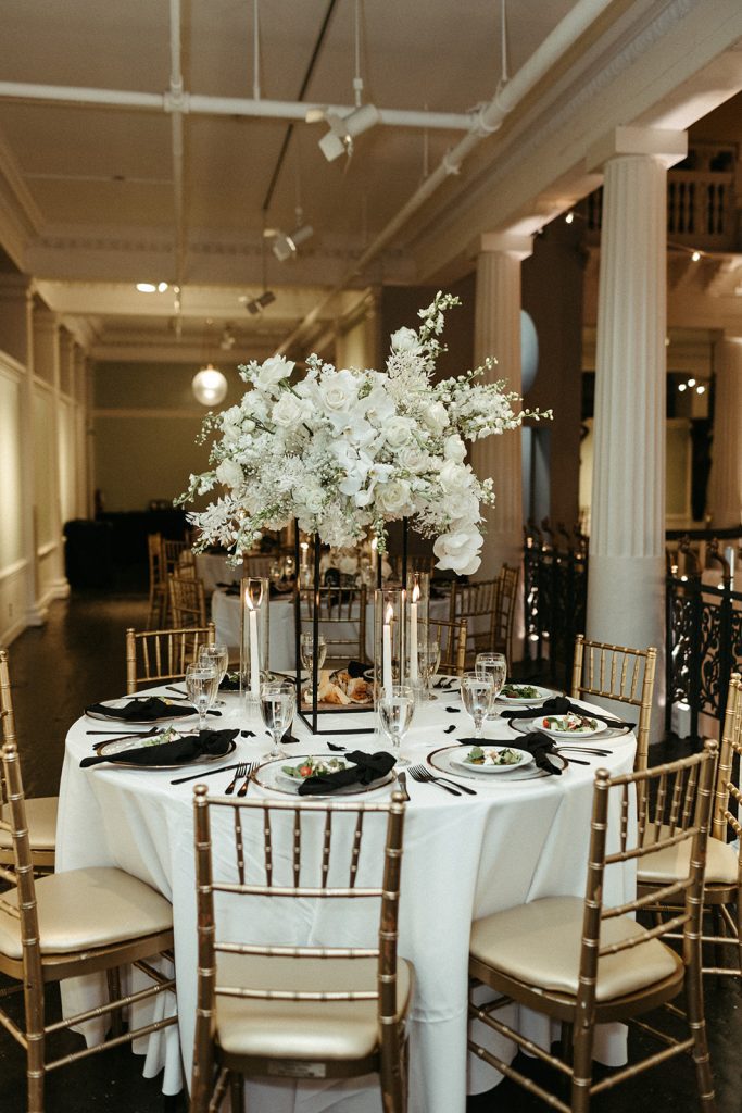 Dinner table decorated with large white flowers for a classic wedding reception at the Lightner Museum.