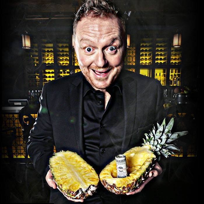 man holding halved pineapple with rolled up money inside