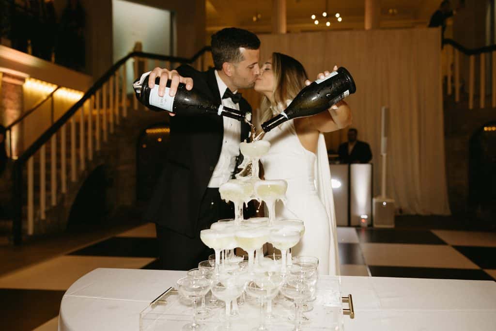 Janine and Daniel pouring champagne into the champagne tower