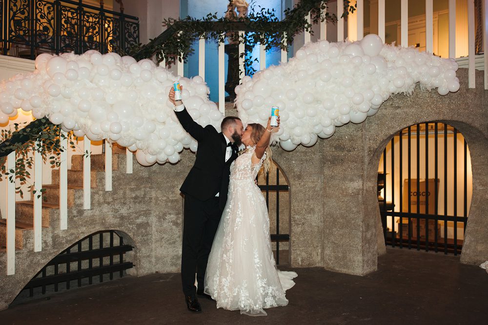 Bride and groom kissing under balloon angel wings