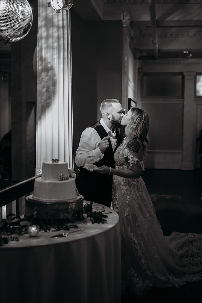 Black and white photo of bride and groom after cutting the cake.