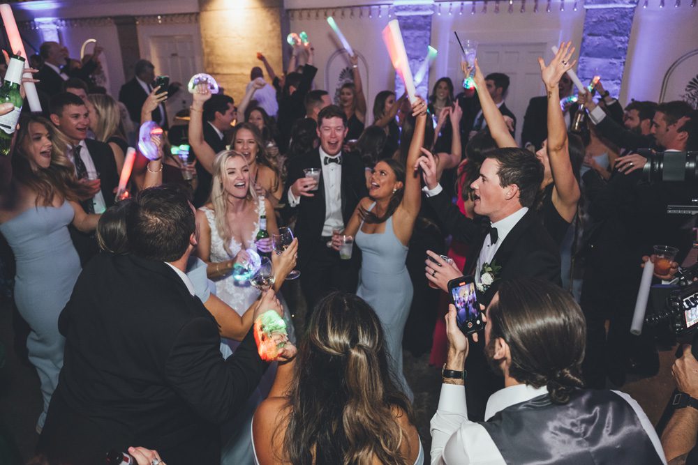 Bride and groom and wedding guests dance with props during reception.