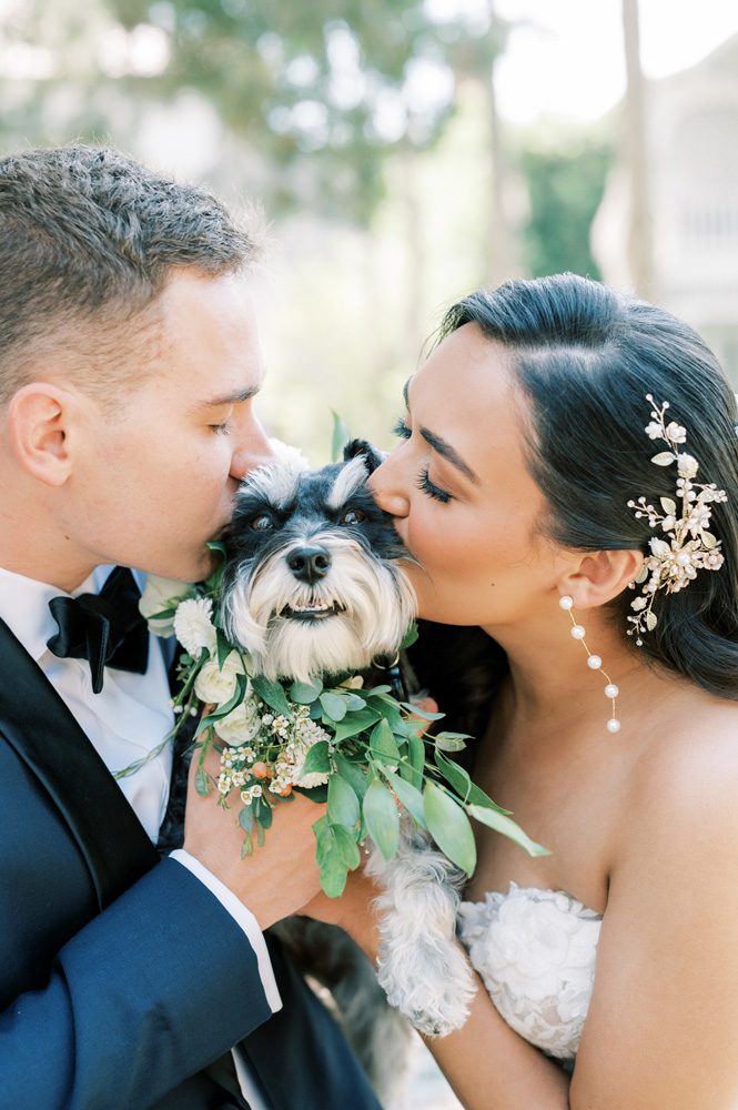 Bride and groom kissing their dog