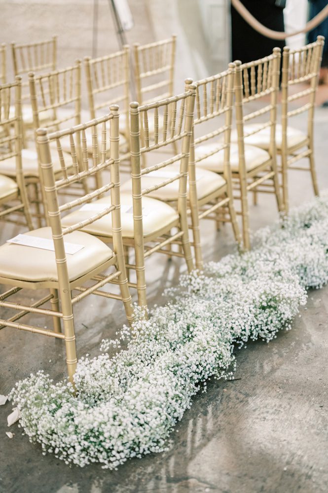 Flowers line the back of chairs for wedding ceremony