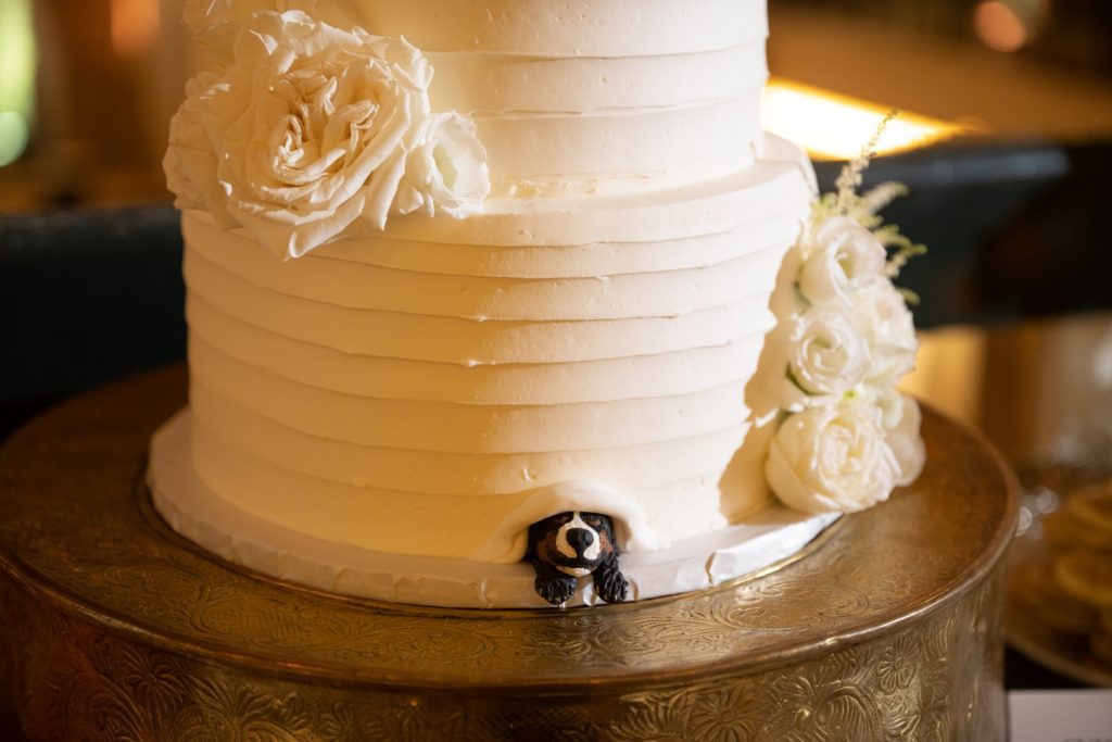 Closeup of wedding cake depicting a dog peeking from underneath the icing