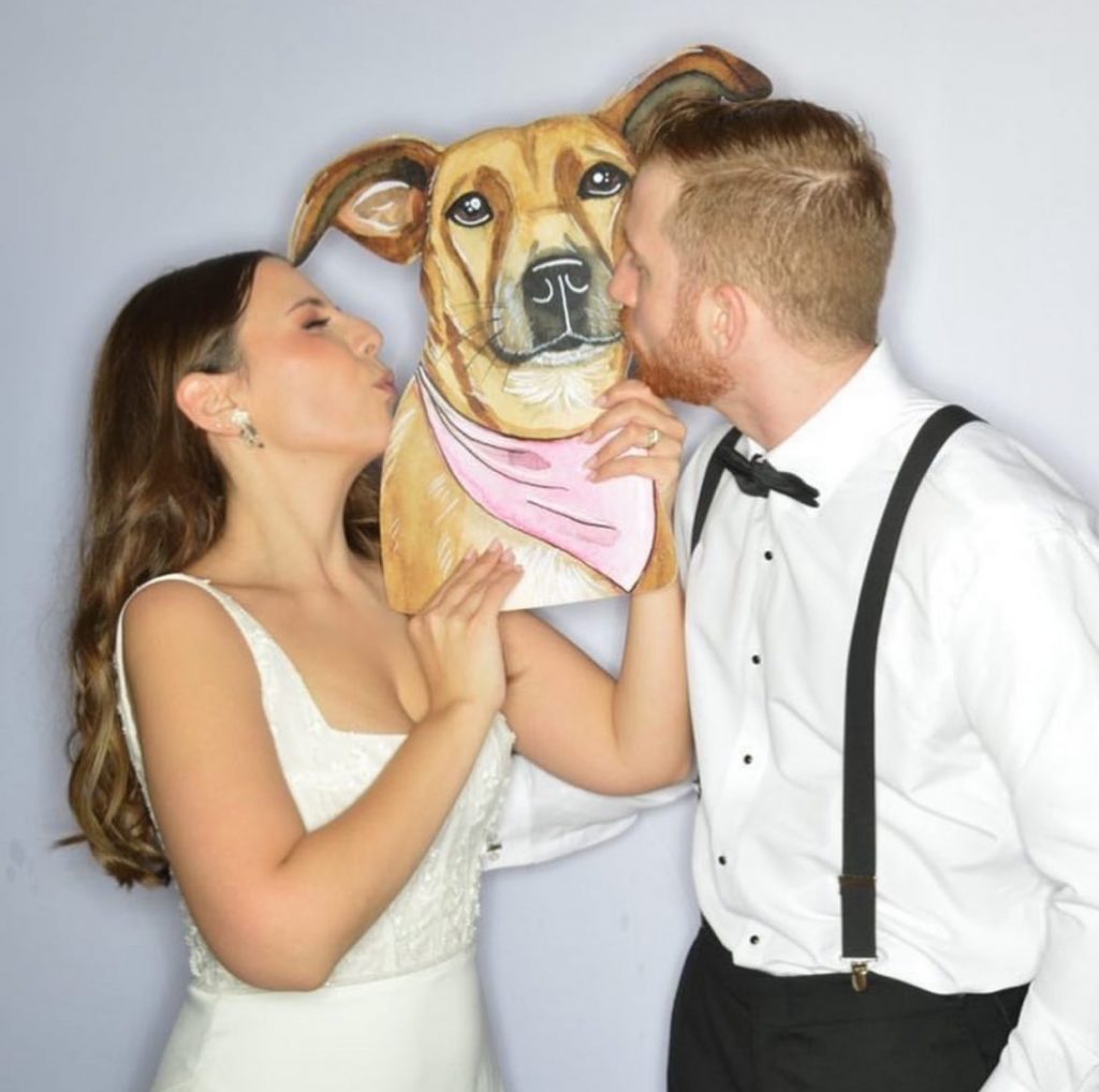 bride and groom kissing a giant custom cutout of their pet
