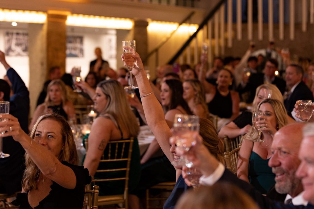 wedding guests raising glasses for champagne toast during reception dinner