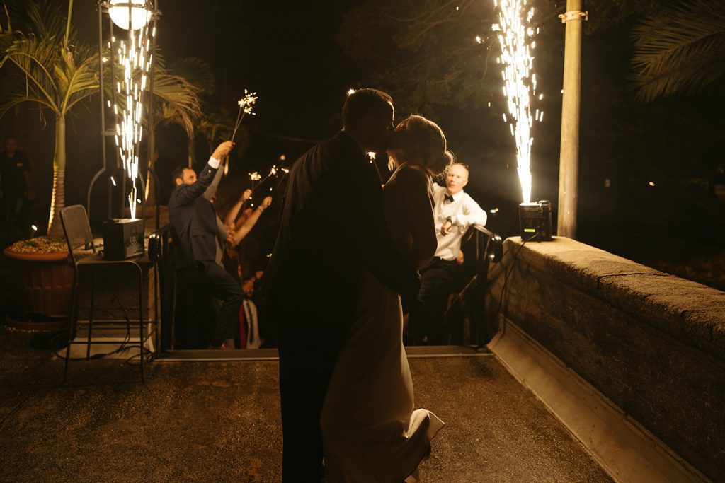 bride and groom kiss with cold spark fountain in background