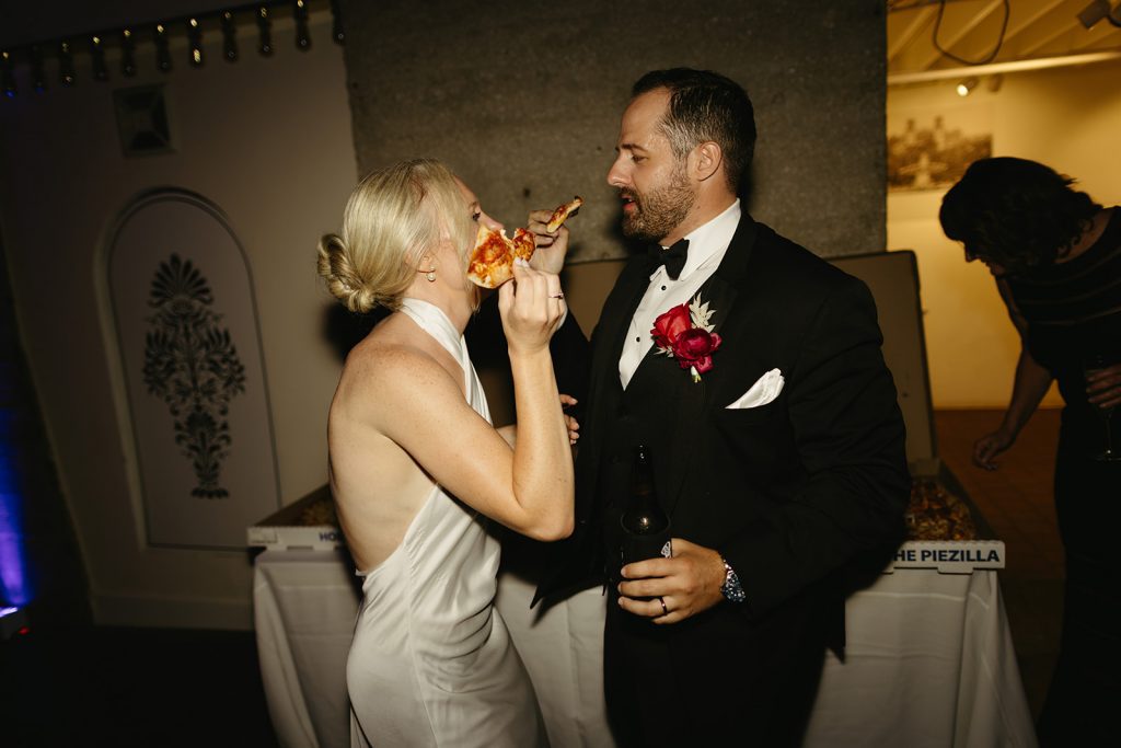 bride and groom sharing a slice of pizza