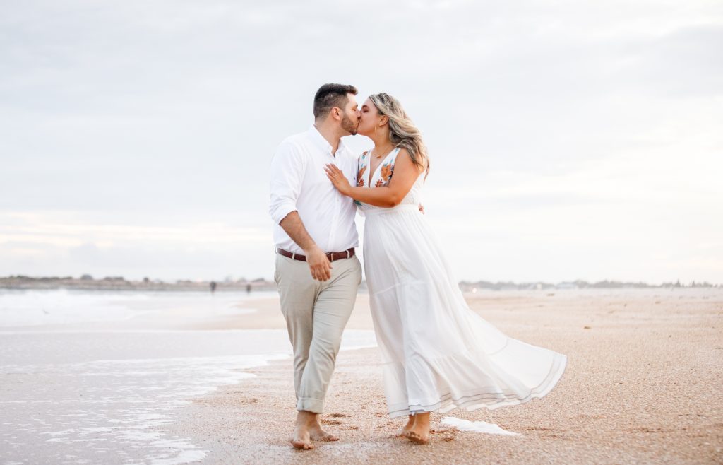 Engaged couple kiss while walking on Vilano Beach
