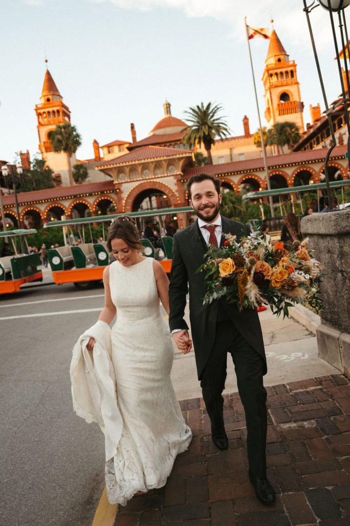 Bride and groom walking down the street in front of Flagler College