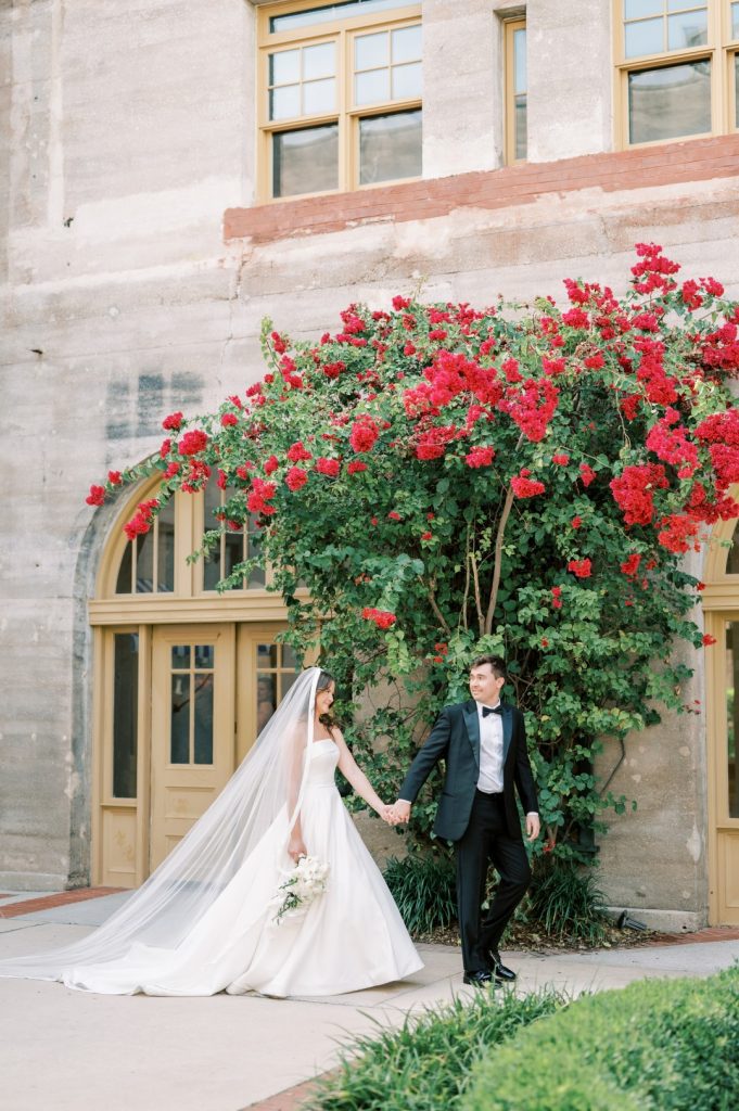 Bride and groom in front of towering bougainvillea 
