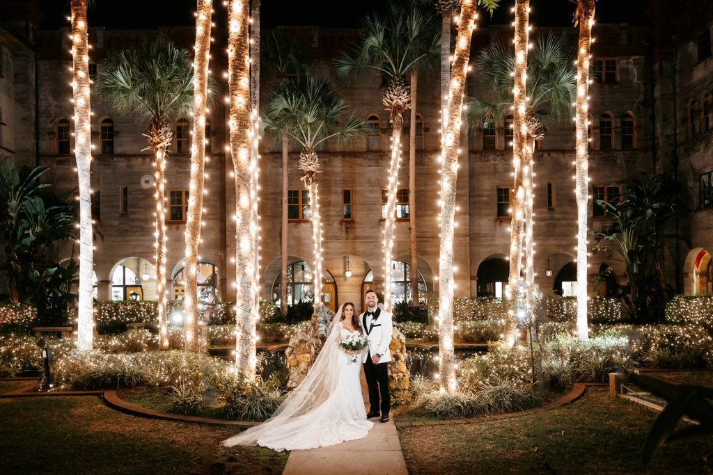 bride and groom outside Lightner Museum with palm trees lit by Christmas lights
