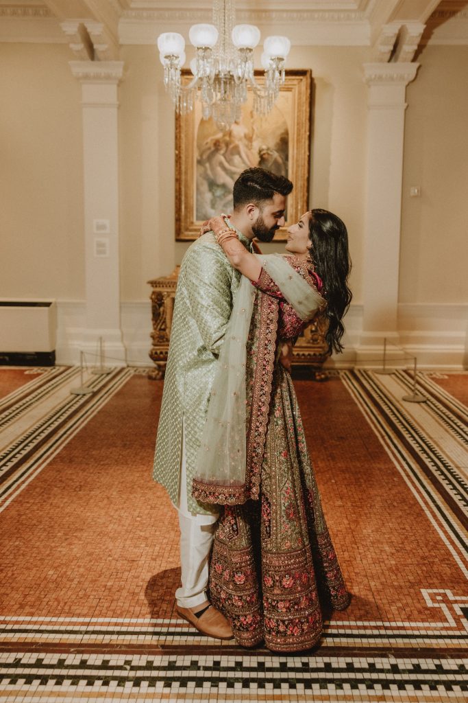 bride and groom in traditional Indian attire embrace in Grand Lobby