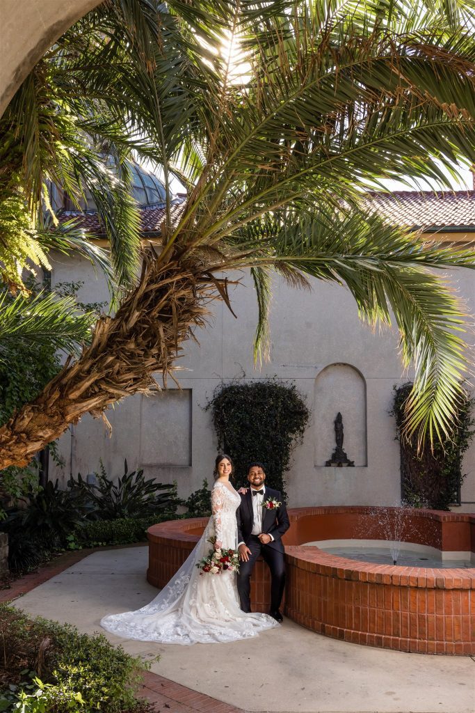 bride and groom sitting by outdoor fountain