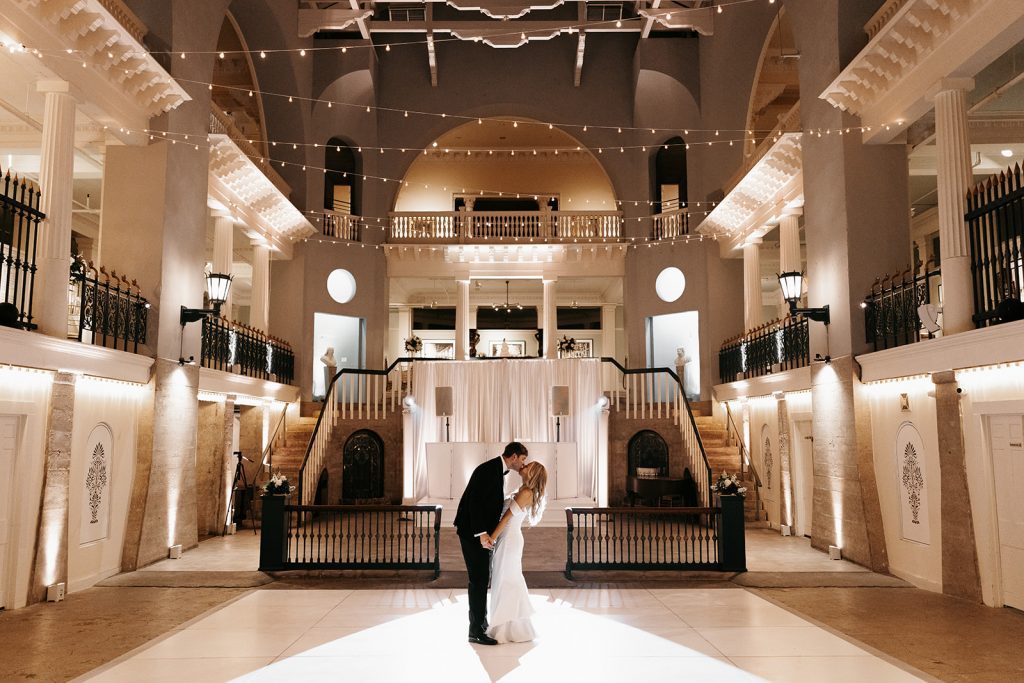 bride and groom kiss in empty reception venue