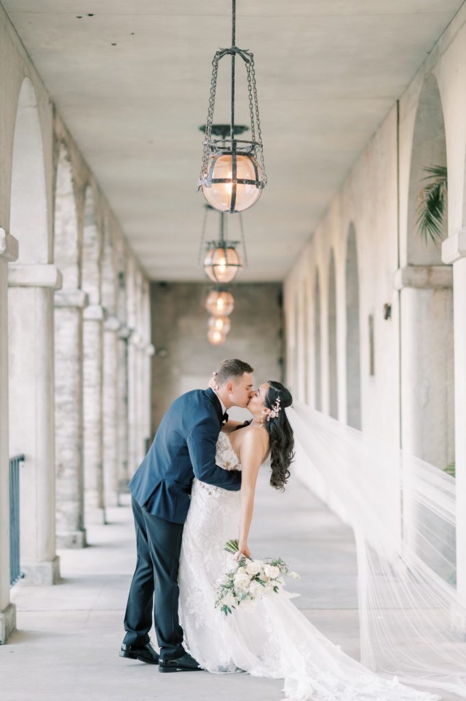groom dipping bride into a kiss underneath covered loggia