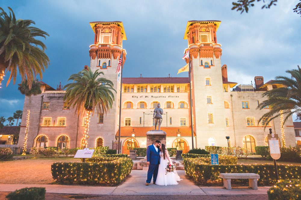 Bride and groom take photos in front of the Lightner Museum on their wedding day